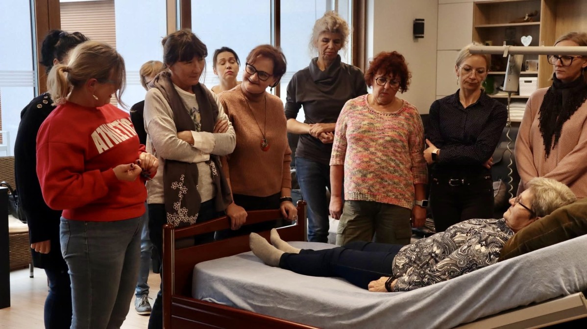 Grupa osób stojąca przy łóżku pacjenta.
